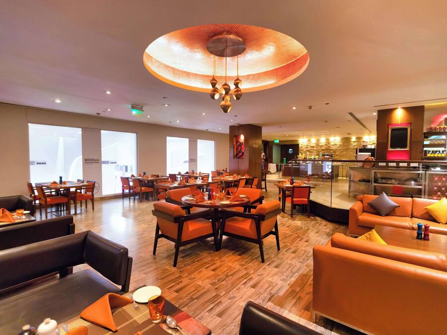A hotel lobby with a dining area, seating arrangements, and a bar.