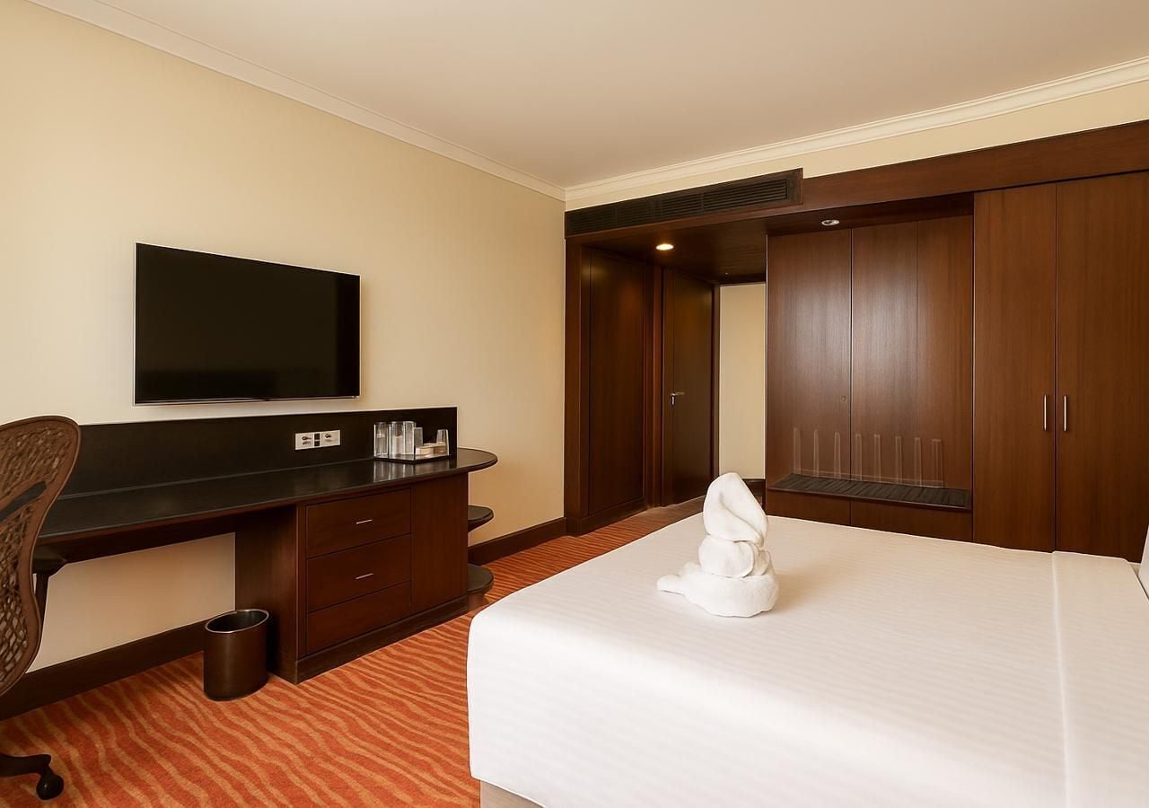 Une chambre d’hôtel équipée d’un lit, d’un bureau, d’une télévision et d’une armoire.