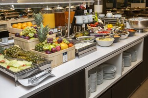 A buffet with various fruits, vegetables, and beverages.