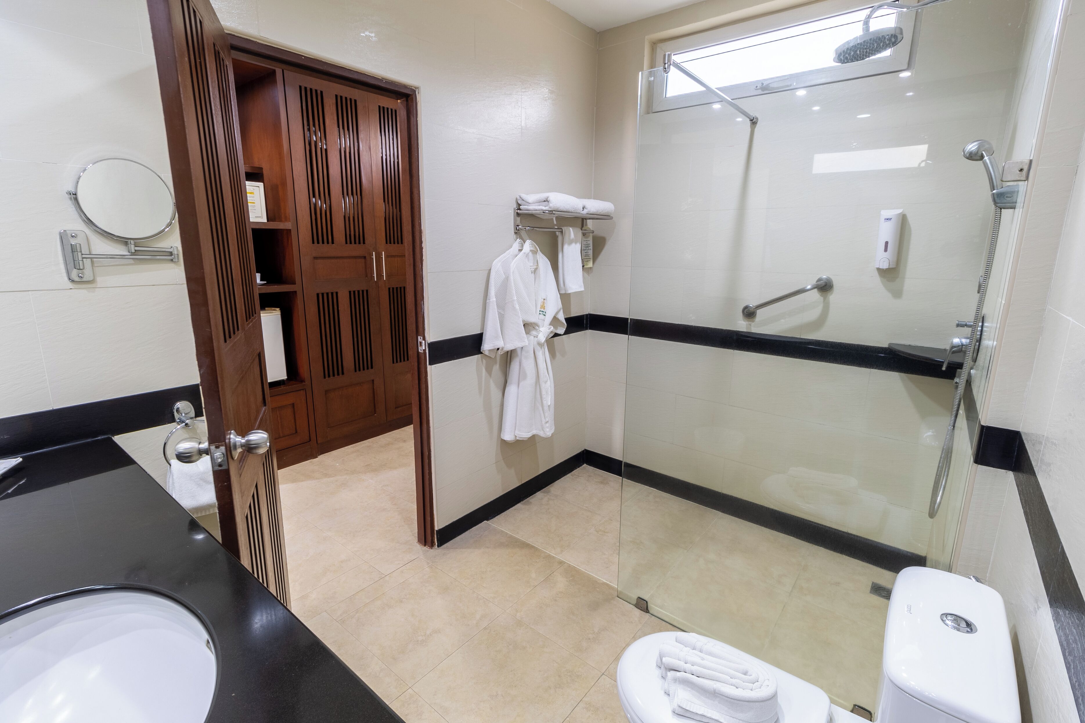 A modern bathroom with a glass-enclosed shower, a black countertop sink, and a white toilet.