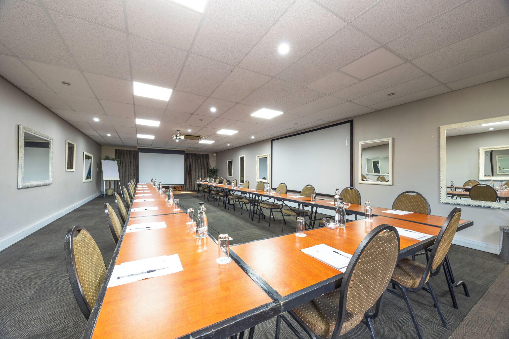 A conference room with a long table, chairs, a projector screen, and a whiteboard.