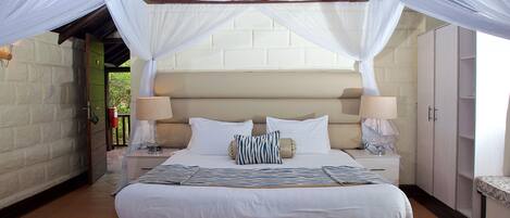 A neatly arranged bedroom with a large bed, bedside lamps, and a wardrobe.