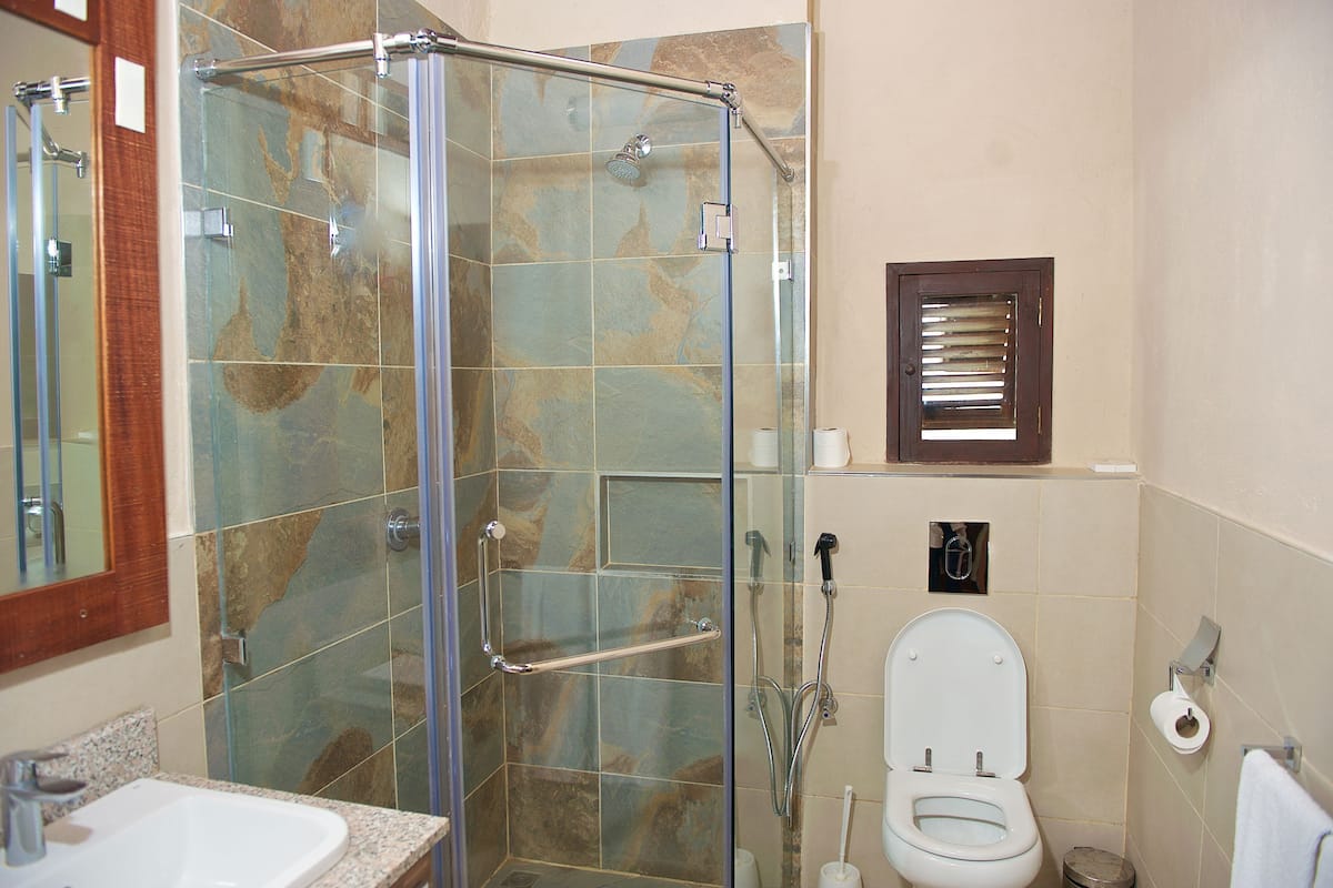 A bathroom with a glass-enclosed shower, a toilet, and a sink.