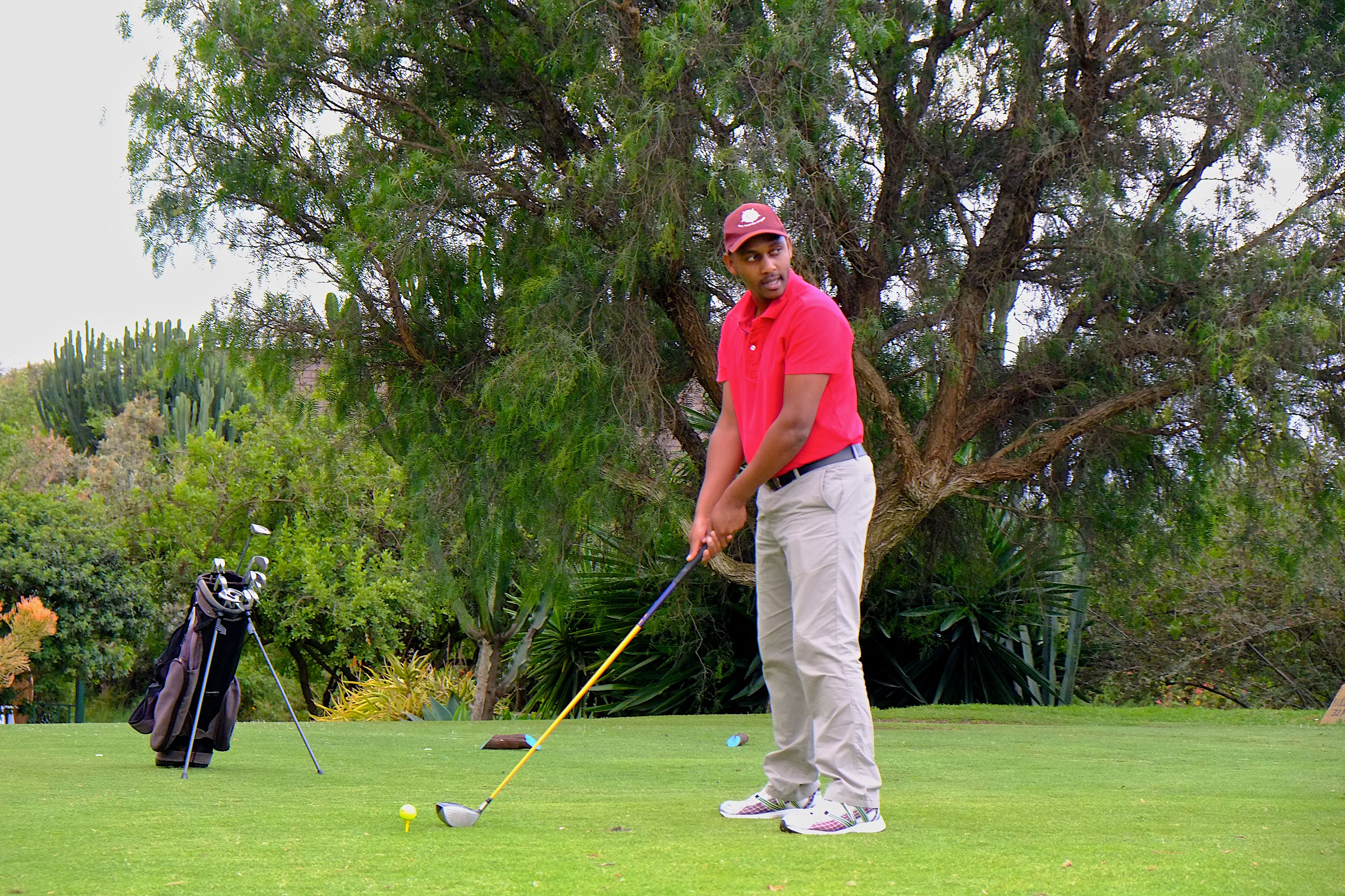 En golfbana med en golfspelare som står bredvid en golfbag och en golfboll på greenen.