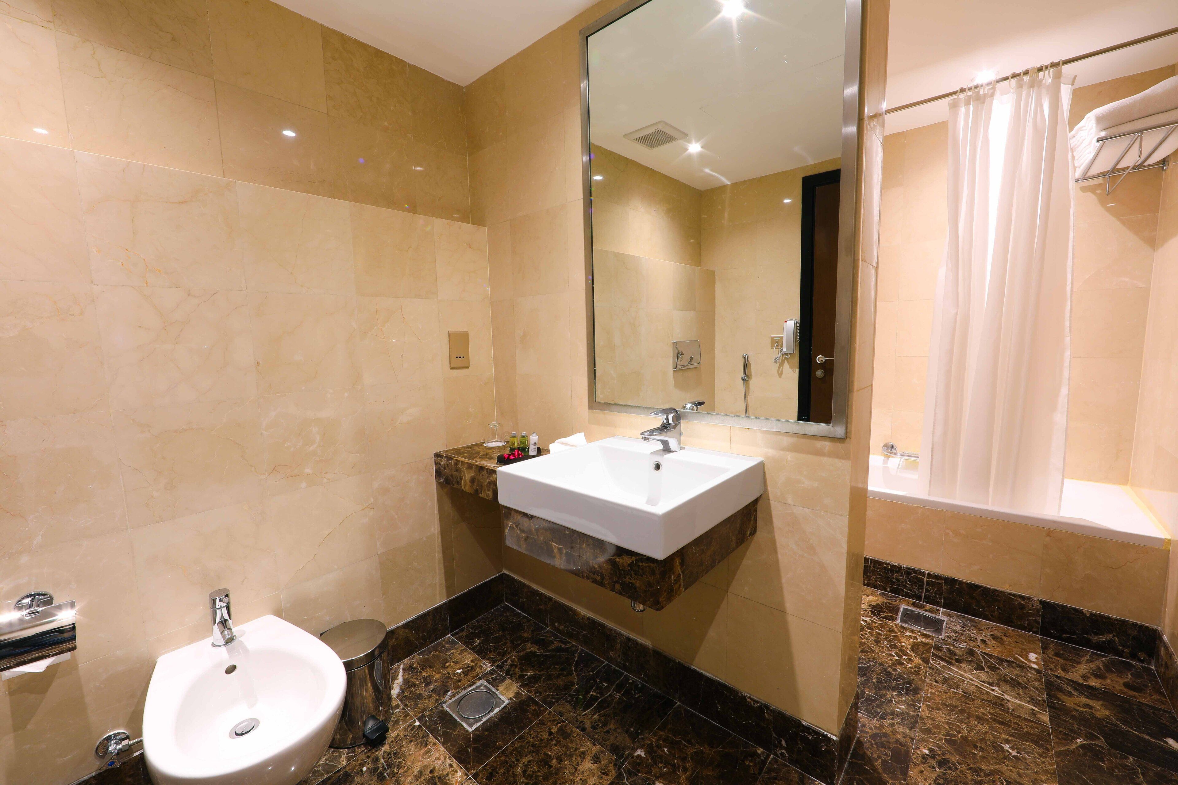 A bathroom with a sink, mirror, and shower.