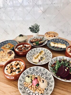 A variety of dishes on a wooden table with a potted plant in the center. - Number One Tower Suites (Dubai)