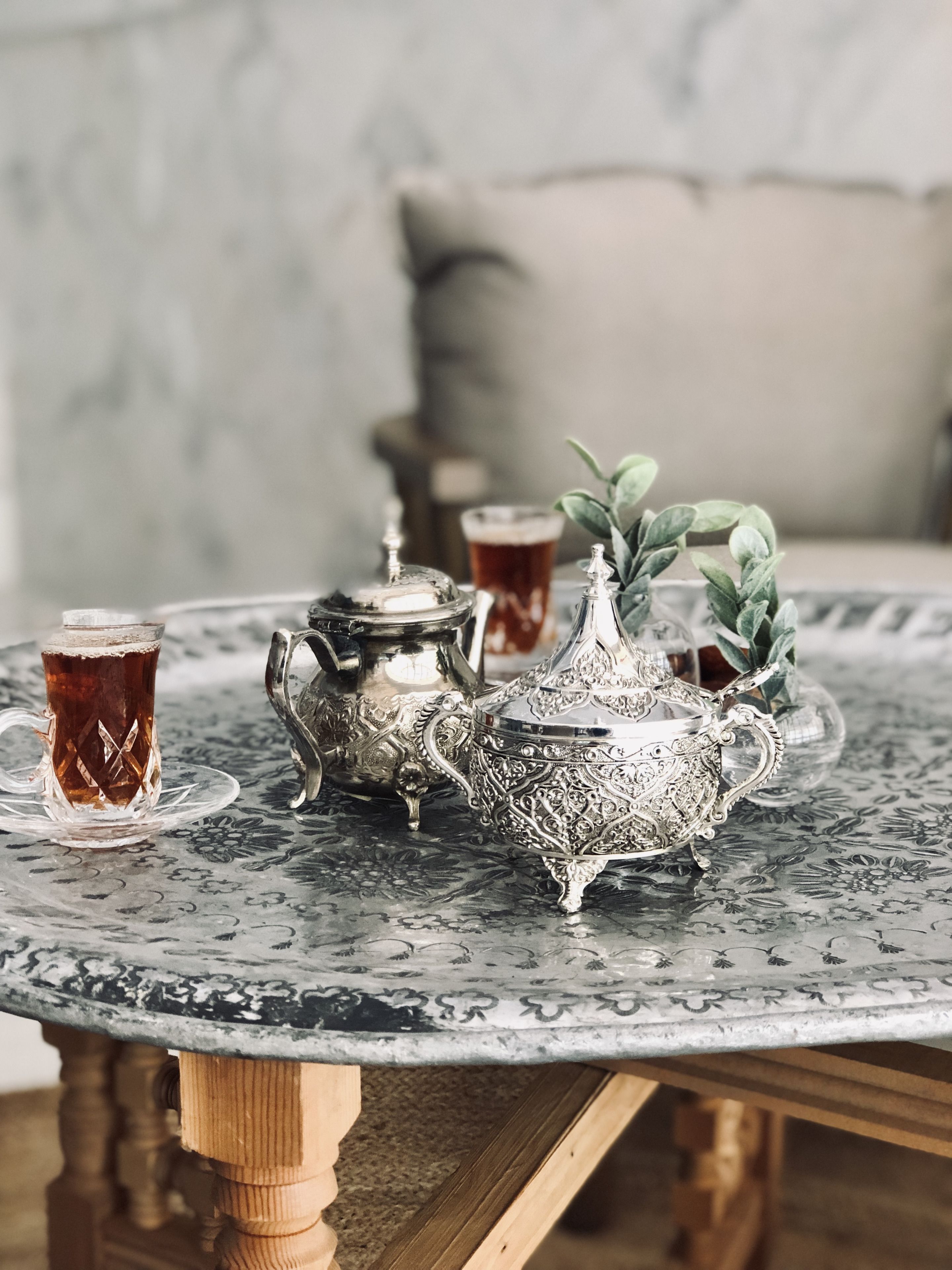 Une table avec un plateau en métal, une théière en argent et deux verres de thé.