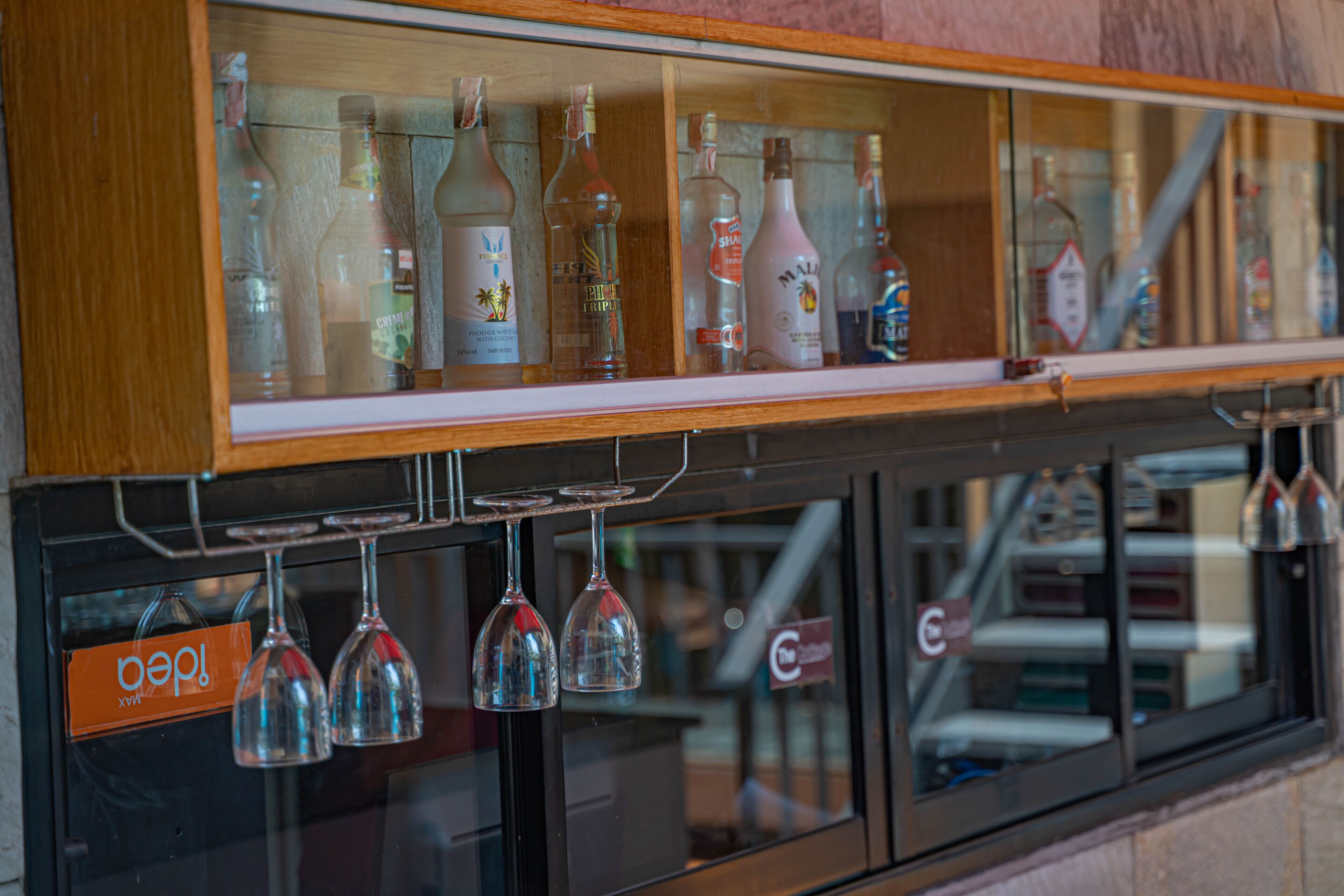 A bar area with various liquor bottles and wine glasses displayed in a wooden cabinet.