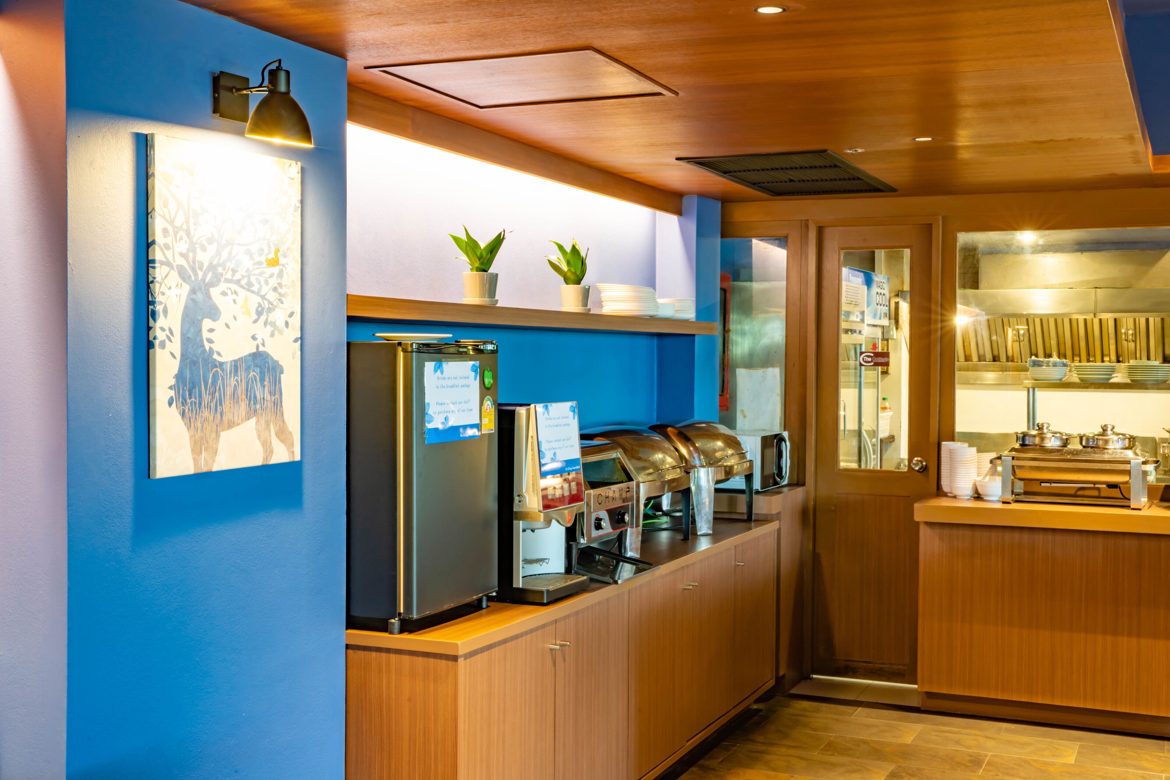 A modern kitchen with a blue wall, a refrigerator, a coffee machine, and a sink.