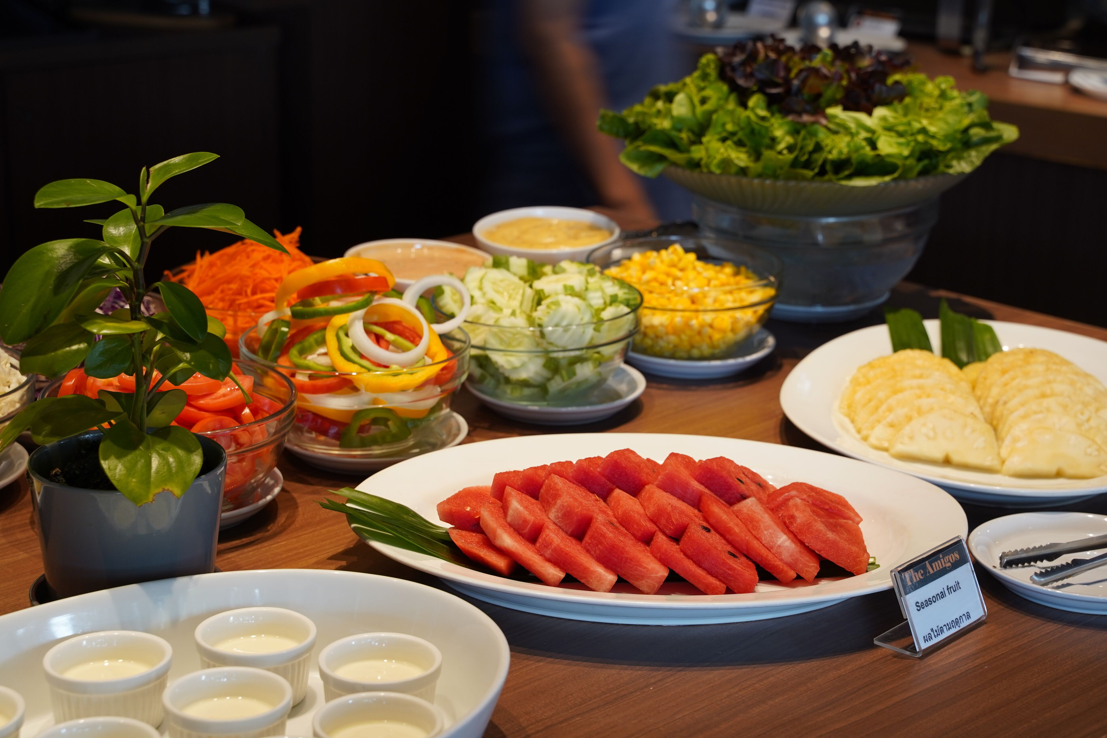 A buffet table with various food items including watermelon, salad, and other dishes.