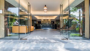 Un área de recepción moderna con puertas de vidrio, mostrador de recepción y asientos.