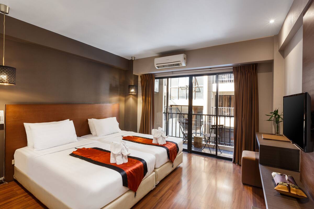 Ein Hotelzimmer mit einem großen Bett, einem Fernseher, einer Klimaanlage und einem Balkon mit Blick.
