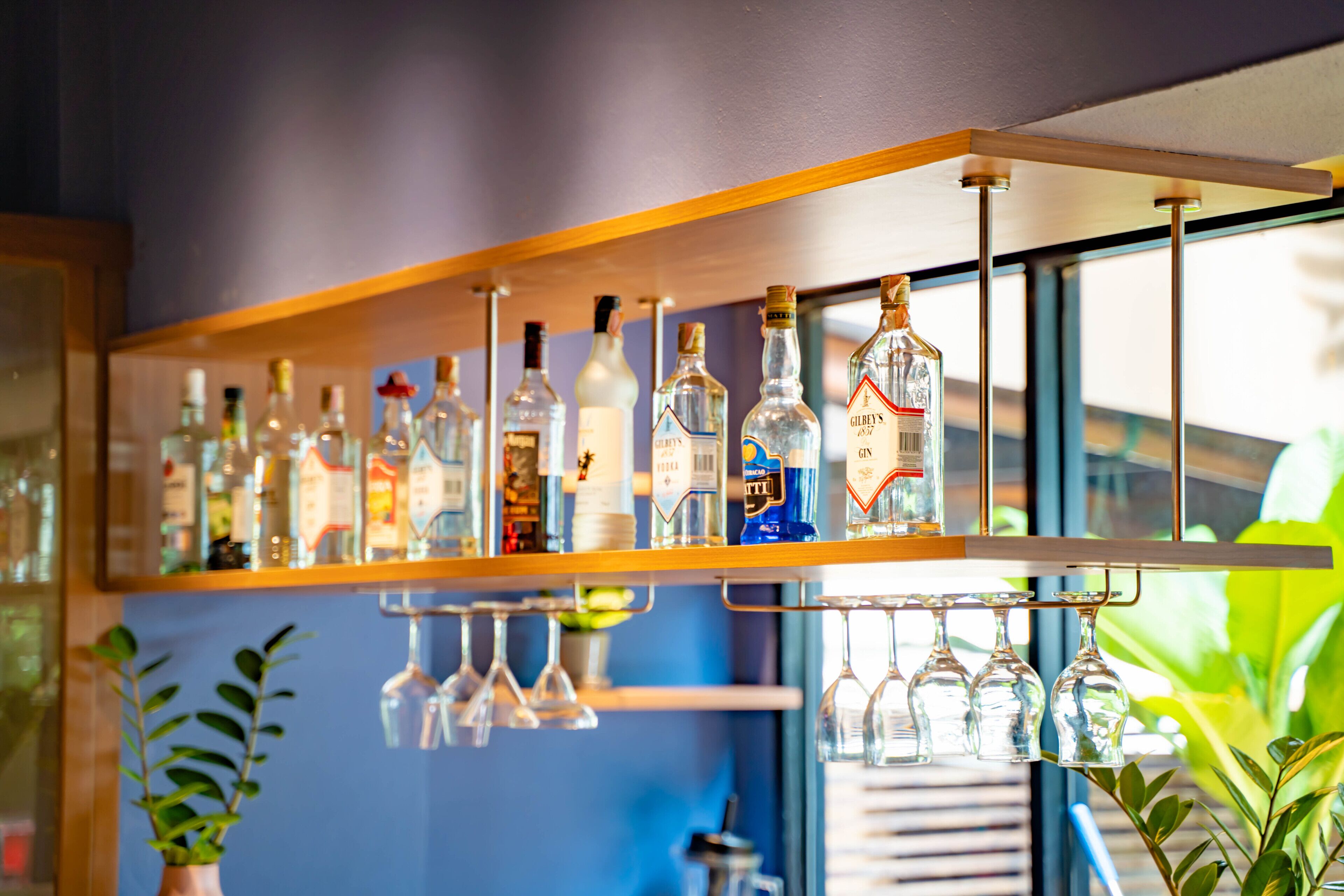 A bar area with shelves holding various bottles and glasses.
