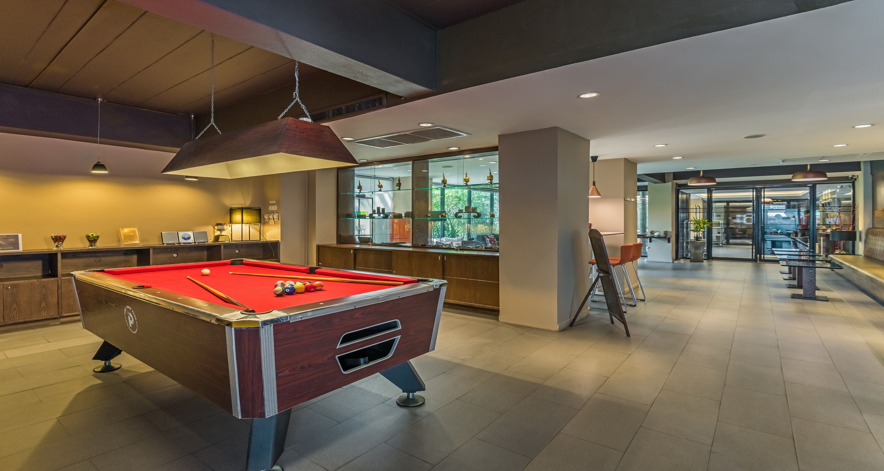 A pool table in a well-lit indoor space with a bar area in the background.