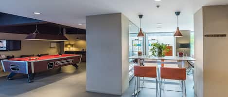 A modern interior with a pool table, bar area, and a sign indicating a restaurant.