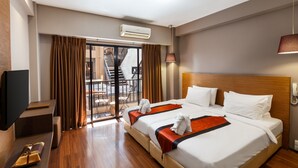 Una habitación de hotel con una cama grande, televisión, escritorio y balcón con cortinas.