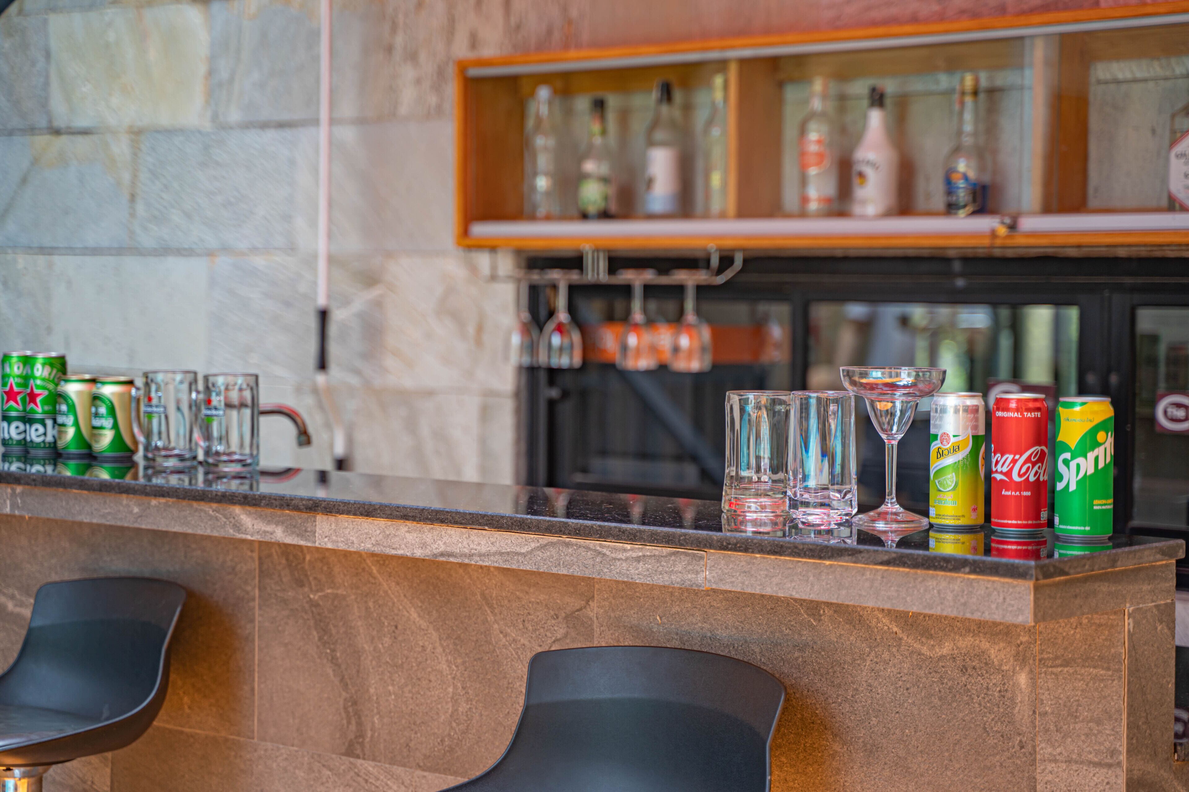 Una zona de bar con una barra que exhibe diversas bebidas y vasos.