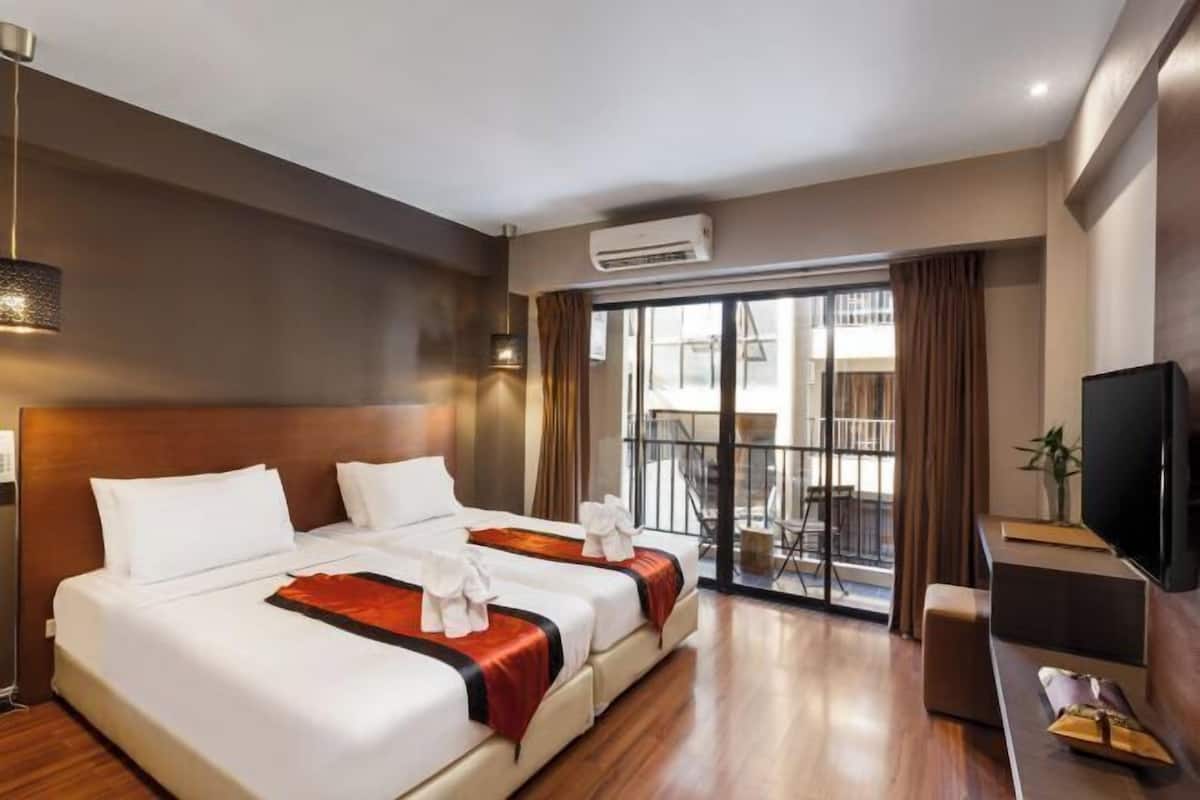 Ein Hotelzimmer mit zwei Betten, einer Klimaanlage, einem Fernseher und einem Balkon mit Blick.