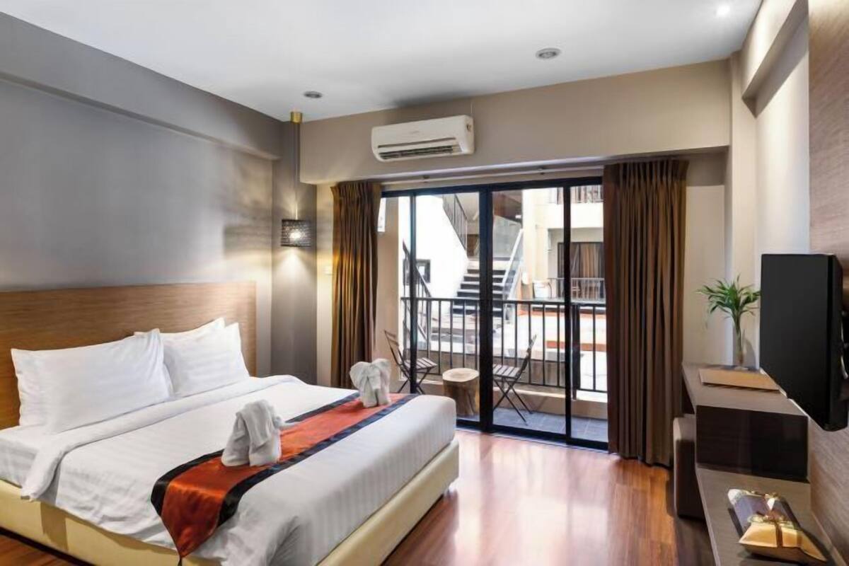 Ein Hotelzimmer mit Bett, Fernseher, einem Balkon mit Blick und einer Treppe.