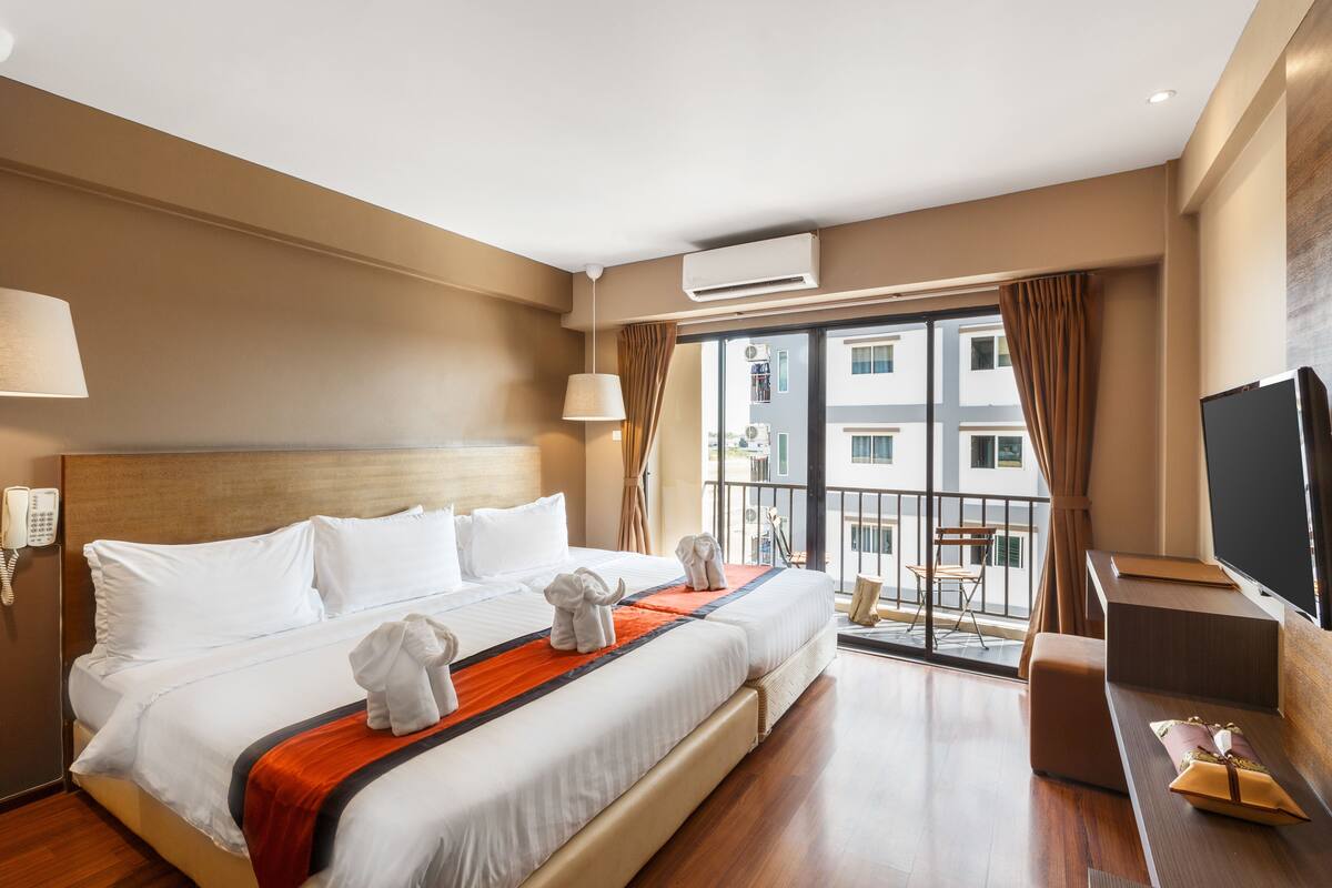 Ein Hotelzimmer mit Bett, Fernseher, Balkon und Klimaanlage.