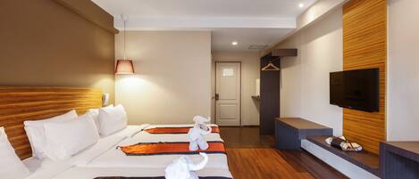 A hotel room with a large bed, a TV mounted on the wall, and a wooden headboard.