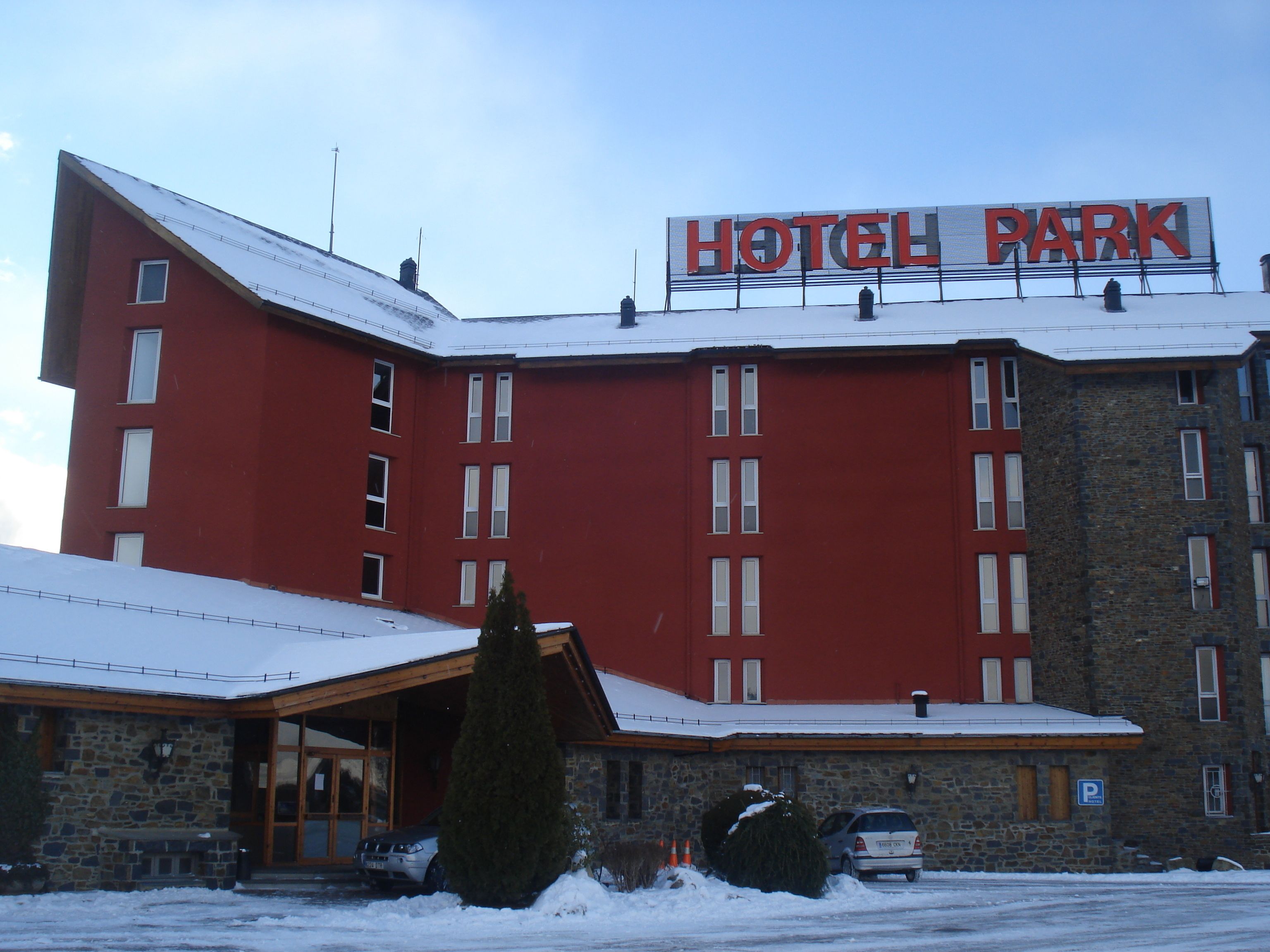A red building with a sign reading "HOTEL PARK" and a stone building with a covered entrance.