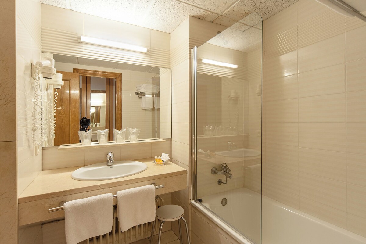 A bathroom with a sink, mirror, and glass-enclosed shower.