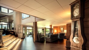 A spacious lobby with a grand clock, comfortable seating, and a staircase leading to an upper level. - Park-Hotel (Puigcerda)