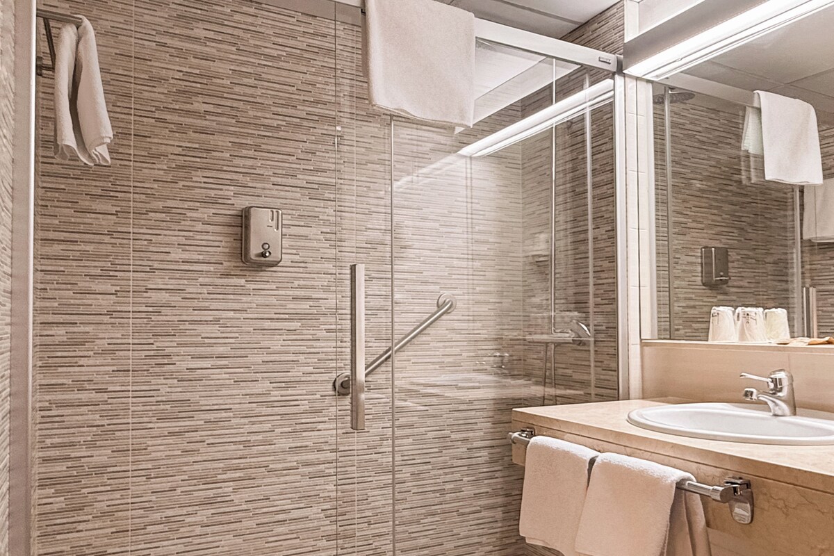 A modern bathroom with a glass-enclosed shower, a sink, and a mirror.