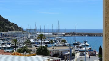 A marina with boats docked, a café with outdoor seating, and a view of the sea.