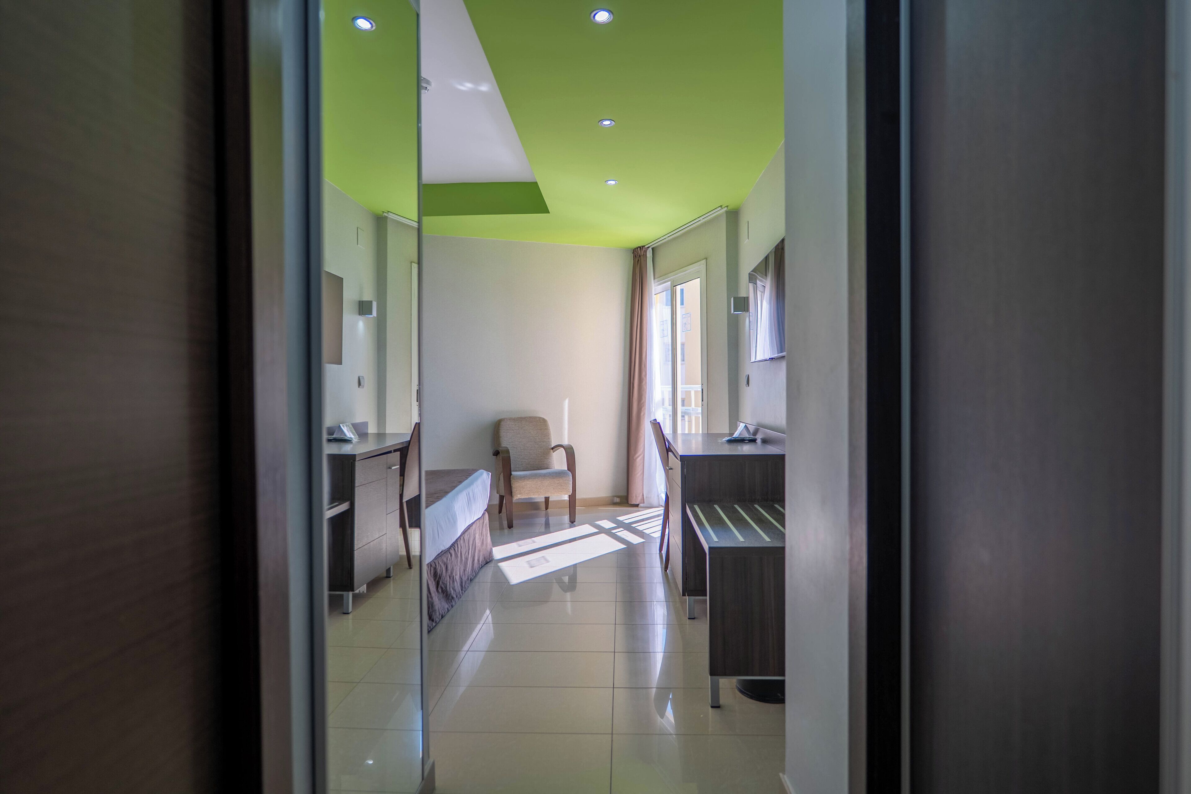 Une chambre d’hôtel avec un lit, une chaise, un bureau et une fenêtre.