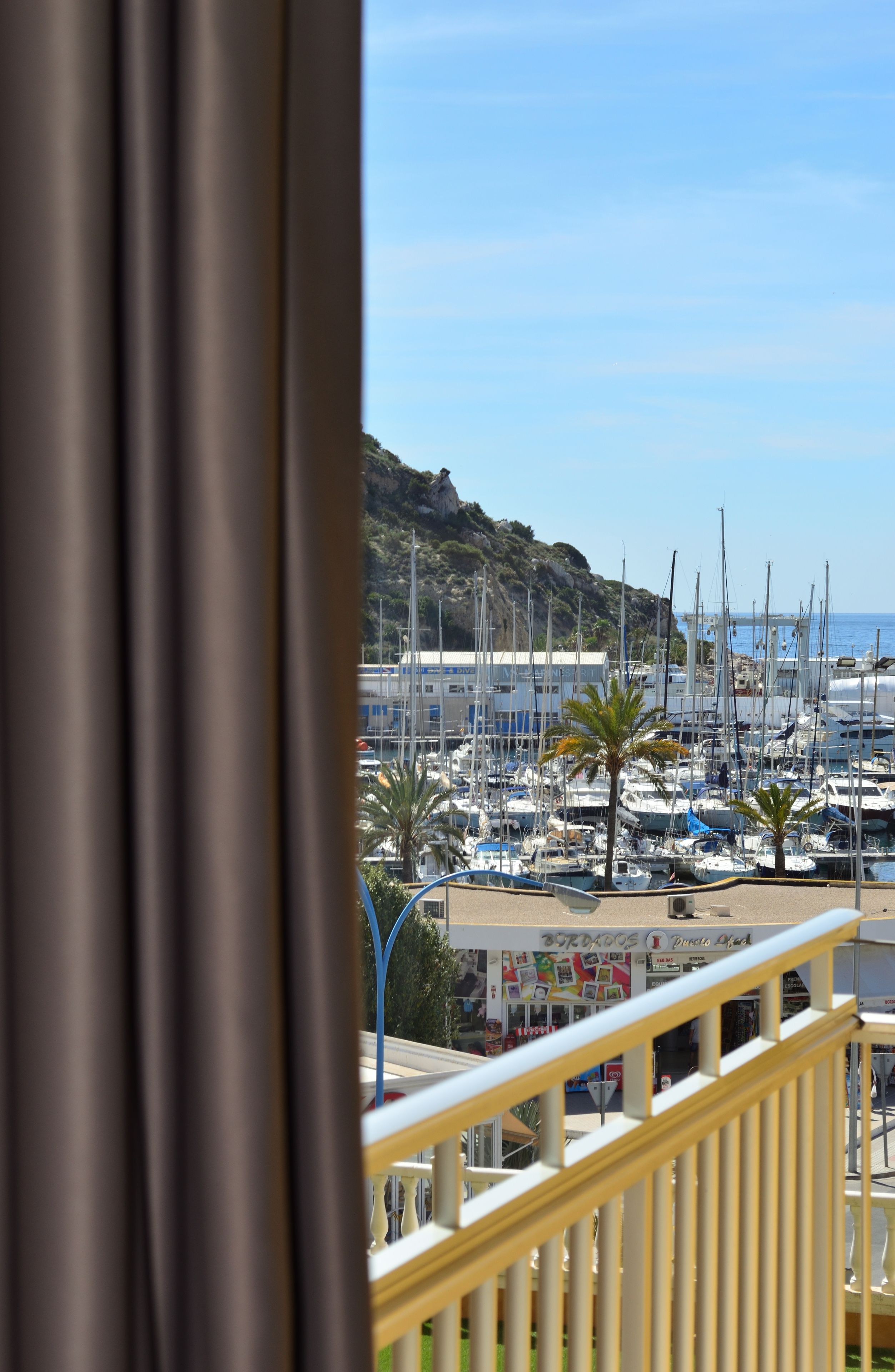 A balcony with a view of a marina, boats, and a mountainous backdrop.