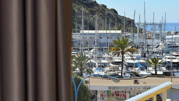 A balcony with a view of a marina, boats, and a mountainous backdrop.