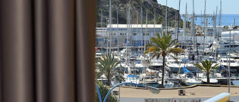 A balcony with a view of a marina, boats, and a mountainous backdrop.