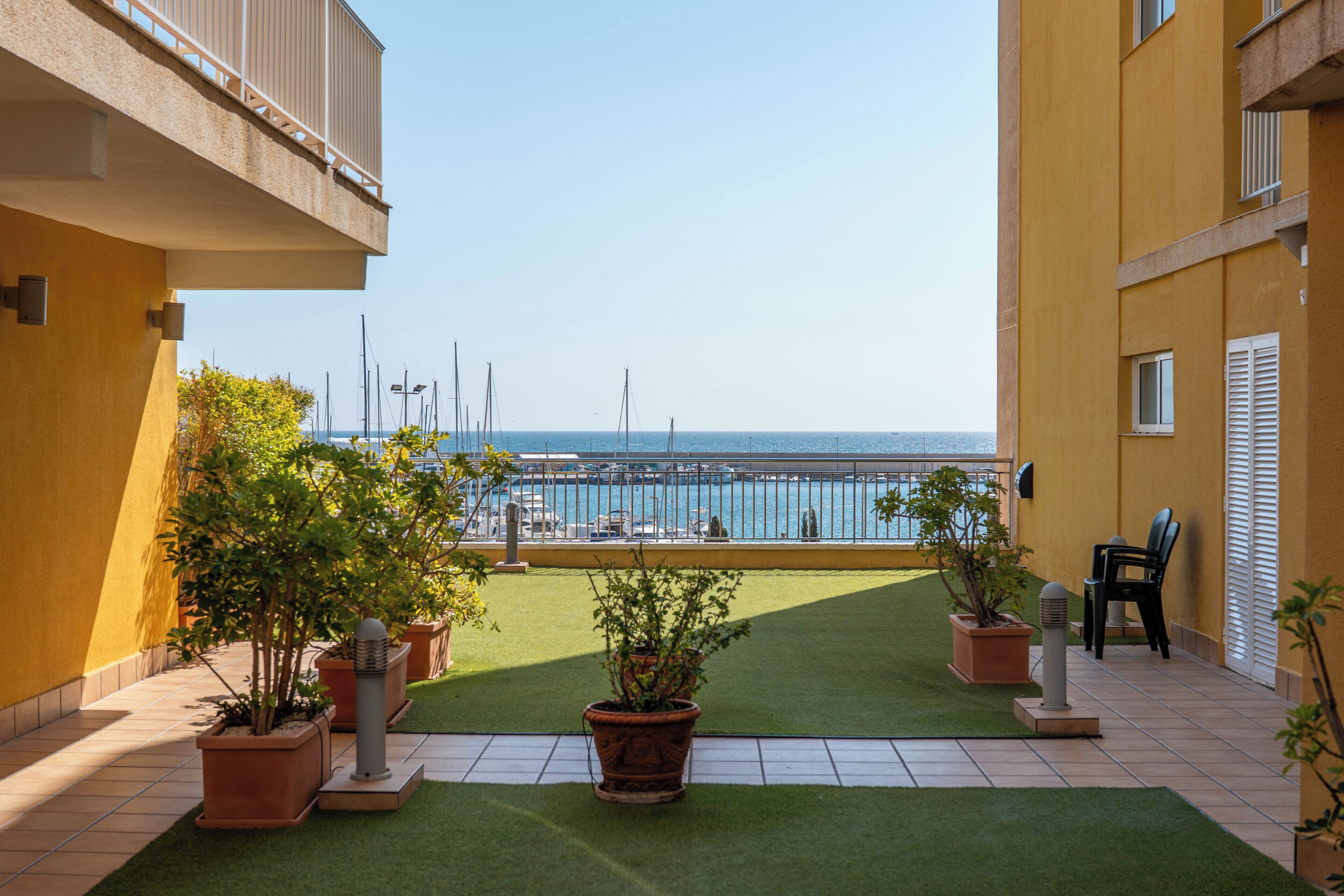 Un balcón con vistas al mar, plantas en macetas y suelo de baldosas.