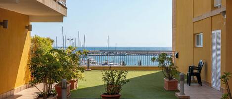 Un balcón con vistas al mar, plantas en macetas y suelo de baldosas.