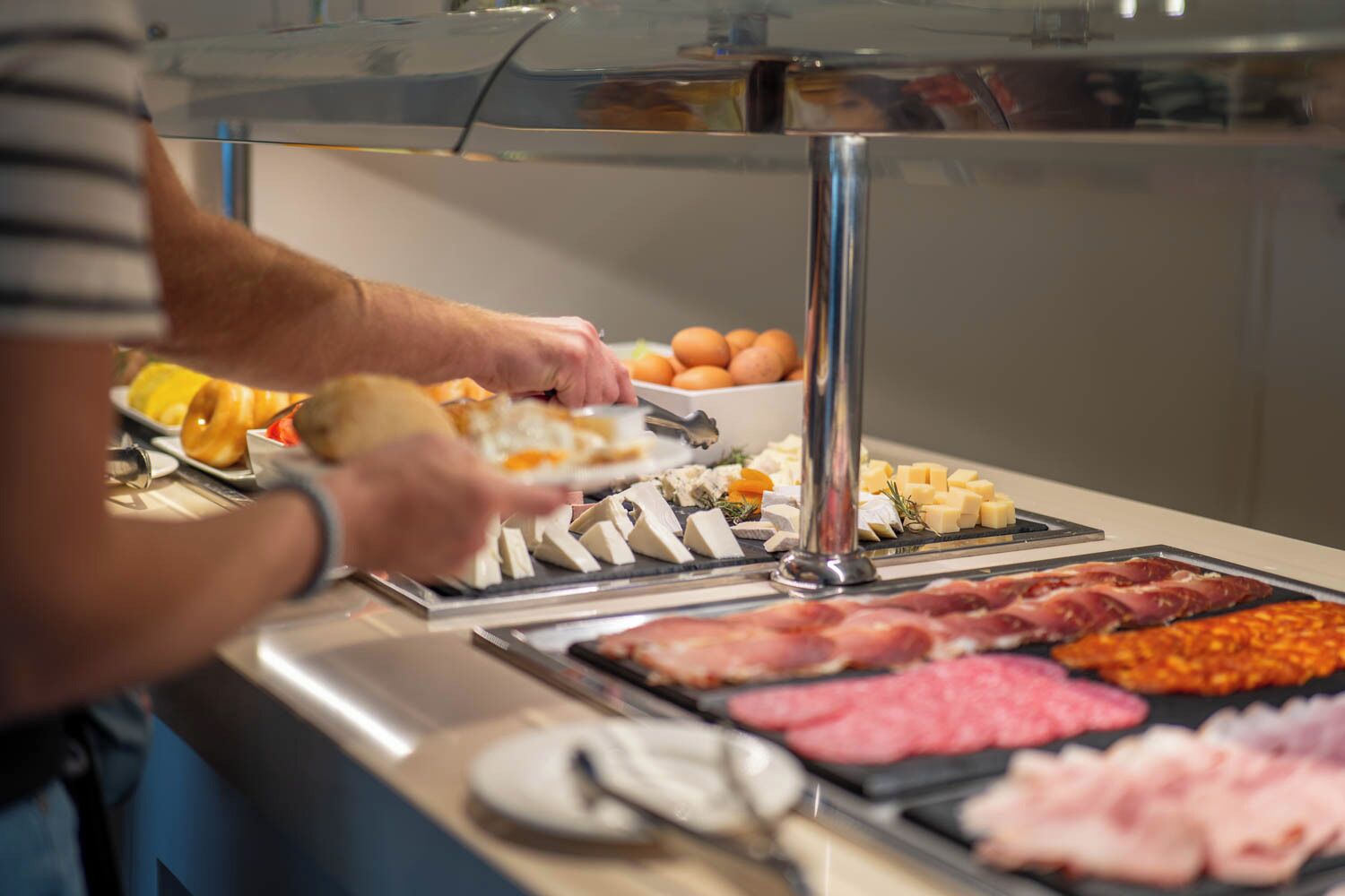A buffet with various food items including meats, cheeses, and eggs.