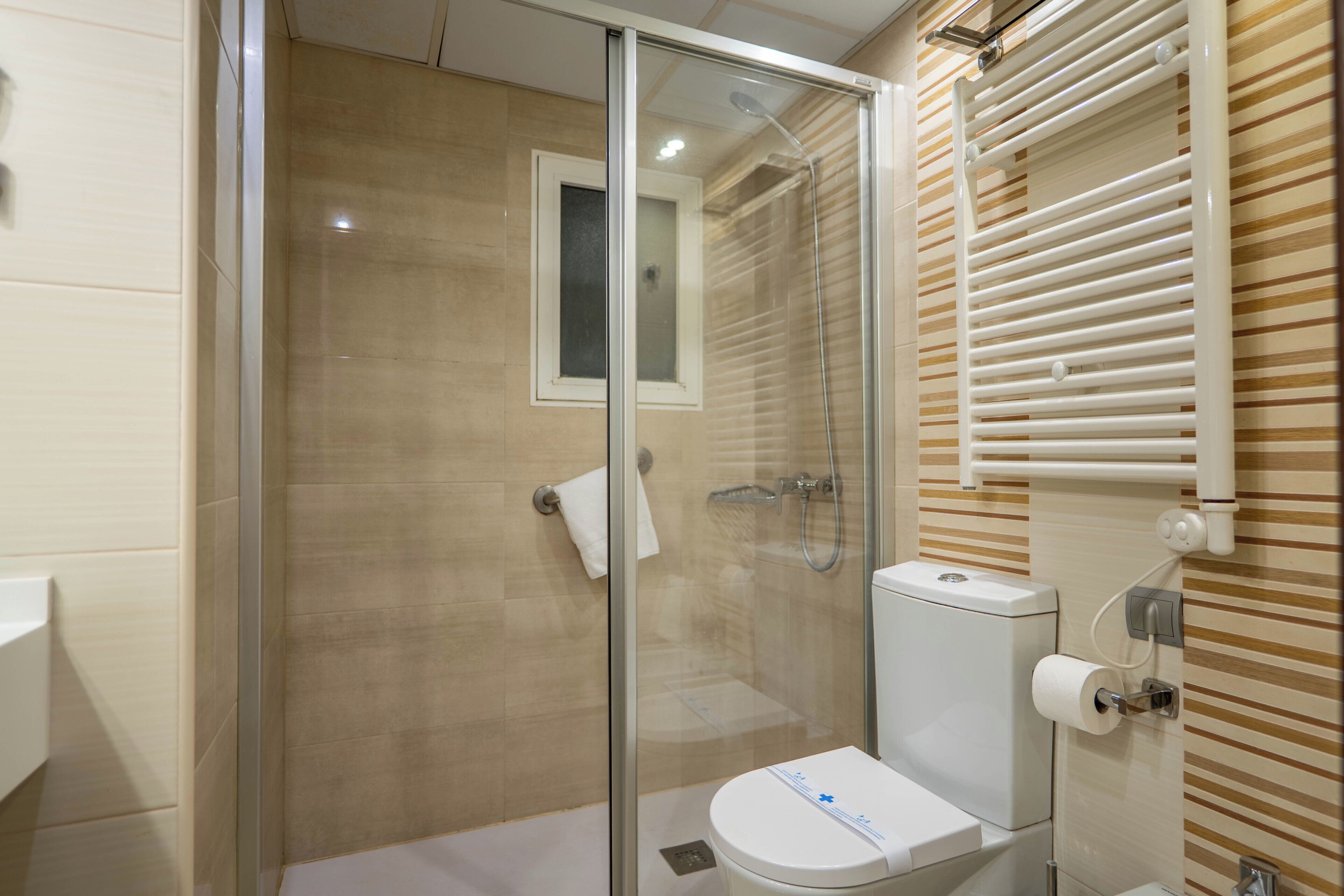 Un baño moderno con ducha de vidrio, inodoro y perchero para toallas.