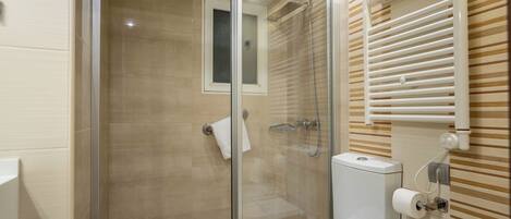 Un baño moderno con ducha de vidrio, inodoro y perchero para toallas.