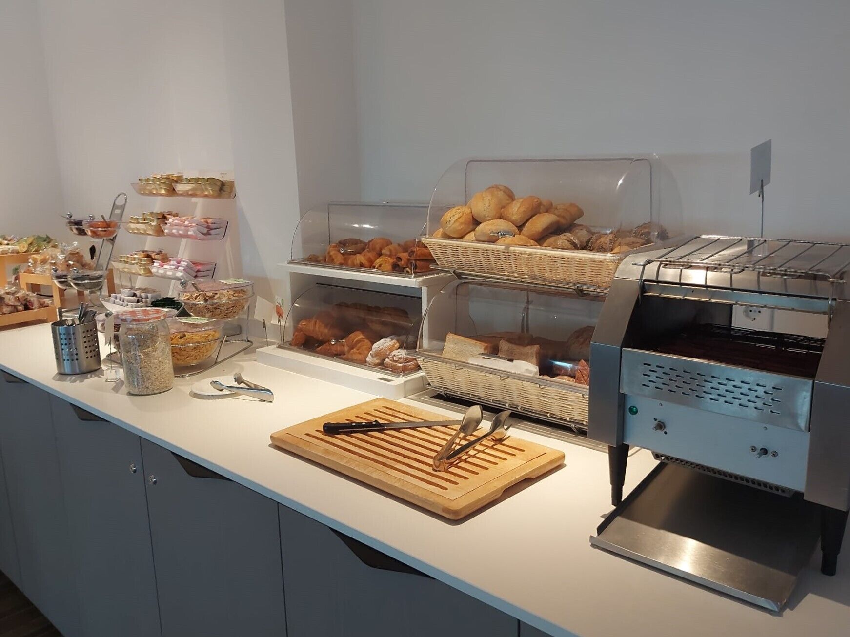 A breakfast buffet with various pastries, bread, and condiments.