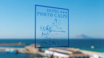 Señal del Hotel Porto Calpe con un paisaje costero de fondo.