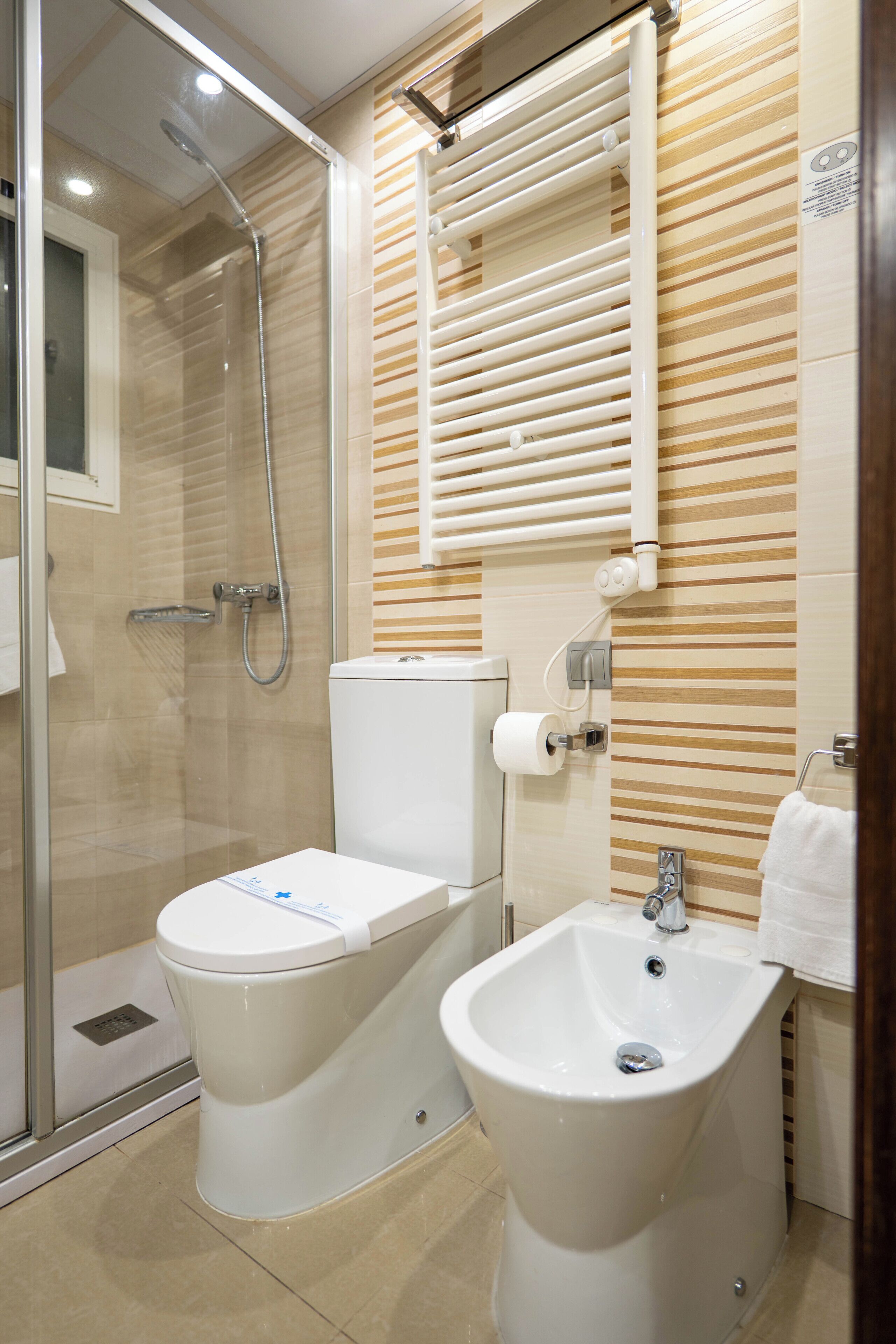 A bathroom with a glass shower enclosure, a toilet, and a bidet.