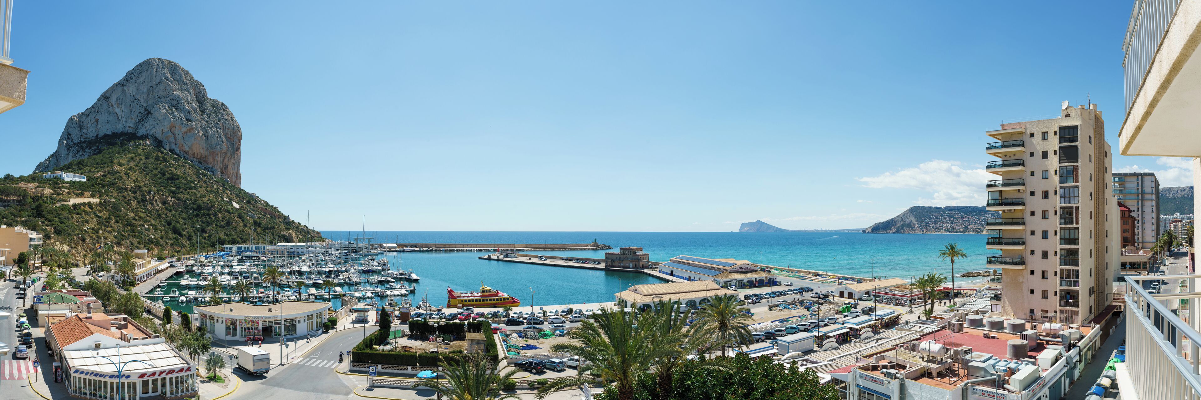 A marina with boats, a restaurant, and a tall building with balconies.