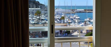 A balcony with a view of a marina, a sign reading "HOTEL PORTO CALPE," and a white railing.