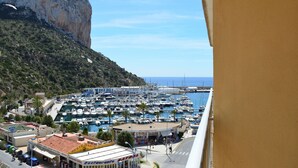 Un puerto deportivo con barcos amarrados, un restaurante y montañas al fondo.