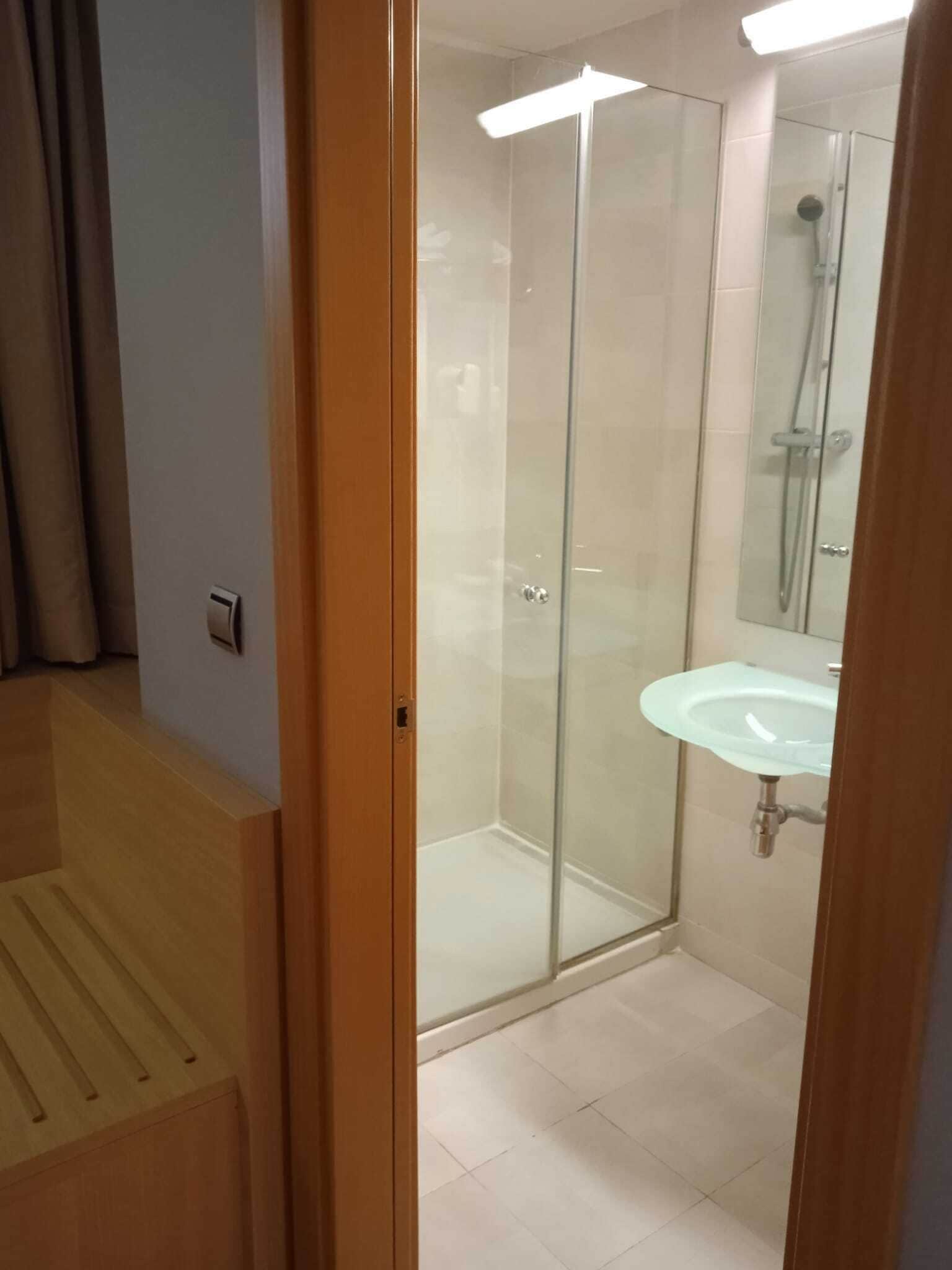 Une salle de bain moderne avec une douche à parois de verre, un lavabo et un miroir.