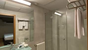 A modern bathroom with a glass-enclosed shower, a glass sink, and a toilet.
