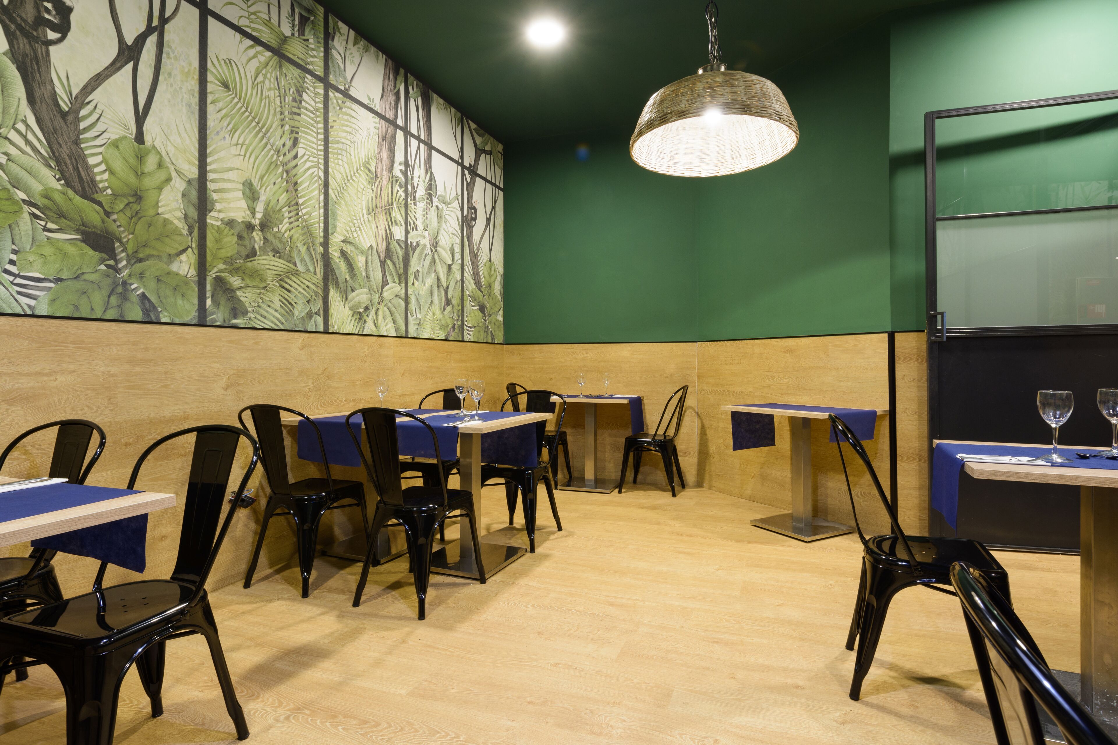 A restaurant with tables and chairs, a large wall mural, and a hanging light fixture.