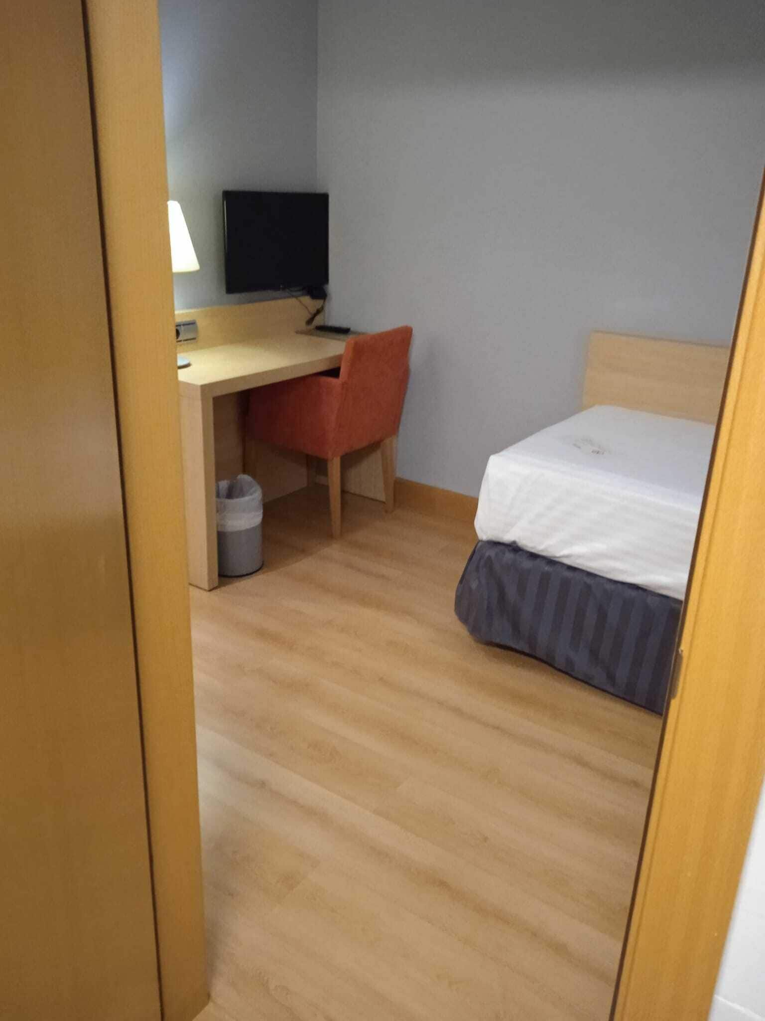 A small room with a bed, a desk, and a chair.