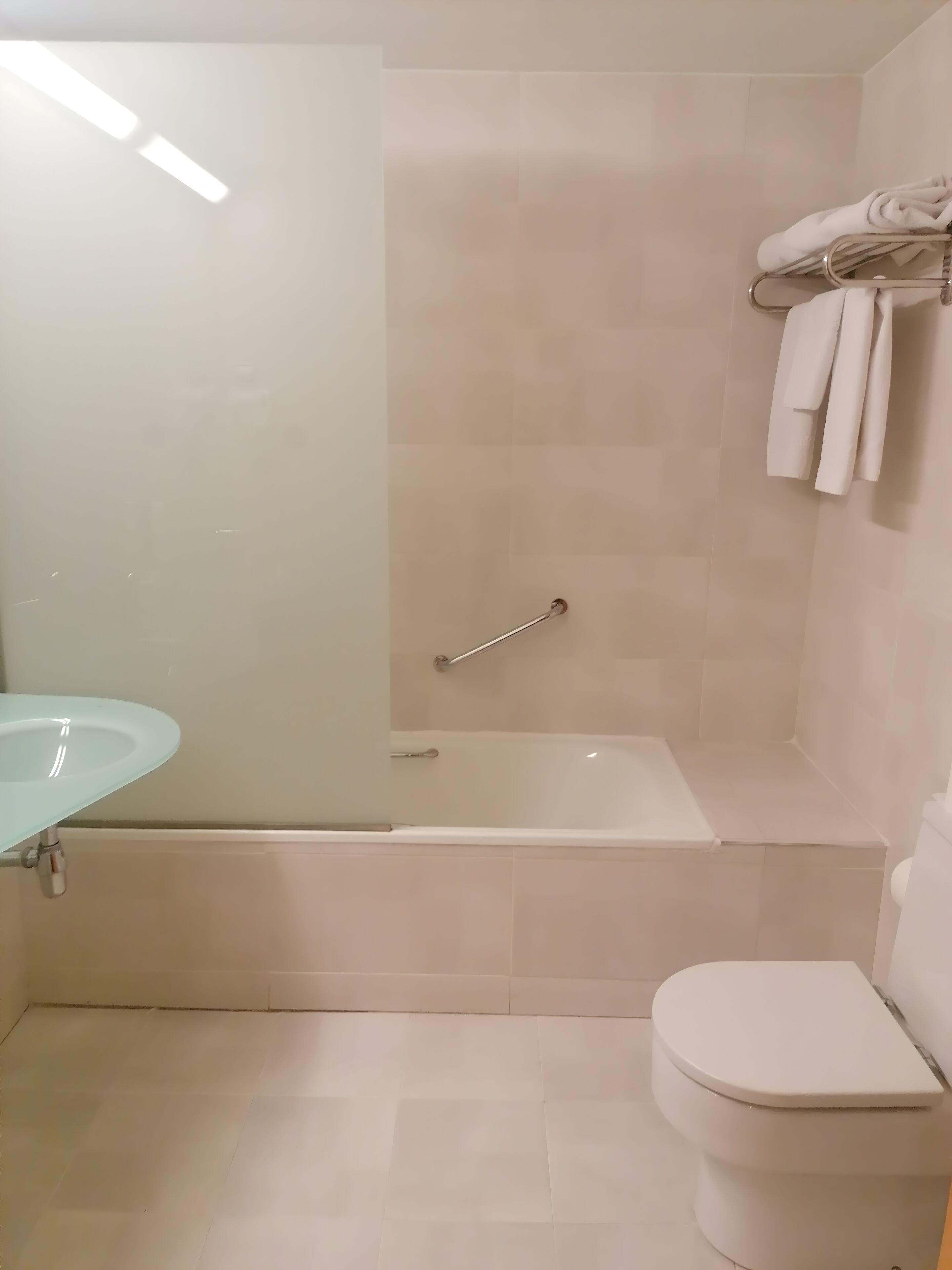 Un baño con ducha envuelta en vidrio, una bañera blanca y un inodoro.